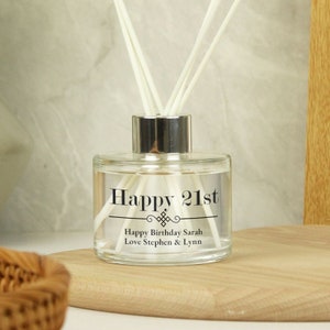 Puede incluir: Una botella de difusor de vidrio transparente con una tapa plateada y texto negro que dice "Happy 21st" con un diseño decorativo y el mensaje "Happy Birthday Sarah Love Stephen & Lynn".