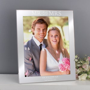 Könnte beinhalten: Silberner Bilderrahmen mit einem weißen Passepartout und einem Foto eines Brautpaares. Der Rahmen trägt die Gravur "Mr. and Mrs. Holloway 29th September 2019" unten.