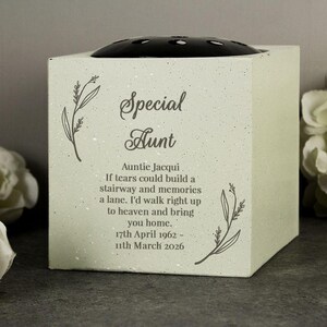 Puede incluir: Un jarrón de flores conmemorativo cuadrado de color verde claro con las palabras "Special Aunt" y un poema impreso en la parte delantera. El jarrón tiene una parte superior negra y circular para arreglar flores y arte lineal floral decorativo.