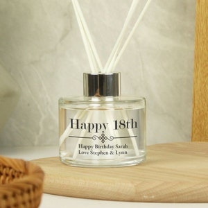 Puede incluir: Una botella de difusor de vidrio transparente con una tapa plateada y texto negro que dice "Happy 18th" y "Happy Birthday Sarah Love Stephen & Lynn".