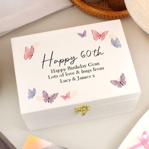 May include: A white wooden box with a gold clasp, decorated with pastel-coloured butterflies. The lid features the text "Happy 60th" and a personalised message. A decorative gift box for a milestone birthday.