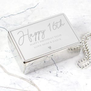 May include: Silver jewelry box with a white lid and a personalized inscription that reads "Happy 16th Happy Birthday Ellie Love Mum & Dad X".