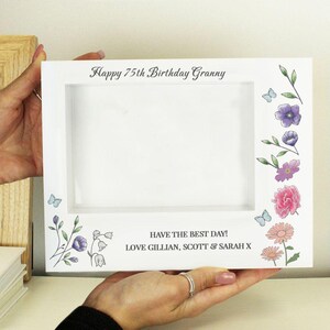 May include: White picture frame with a floral design and the text "Happy 75th Birthday Granny" and "Have the best day! Love Gillian, Scott & Sarah X".