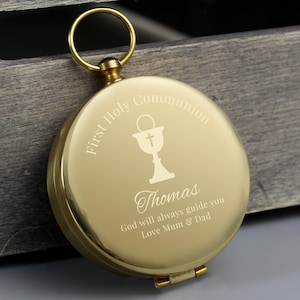 May include: Gold compass with a First Holy Communion inscription, a chalice icon, and the name Thomas. The compass also includes the text "God will always guide you Love Mum & Dad".