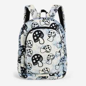 May include: A backpack featuring a light blue and white tie-dye pattern with a repeating black mushroom print. The bag includes a front zippered pocket, a main compartment with a black zipper closure, and two padded shoulder straps on the back.