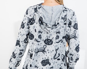 May include: A gray hooded sweatshirt with a black and white print of cats, stars, and crystals. The sweatshirt has long sleeves and a relaxed fit.
