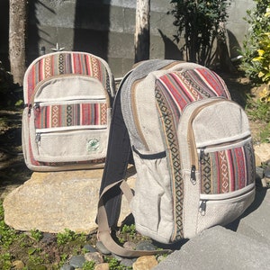 Könnte beinhalten: Zwei Hanf-Rucksäcke mit bunten geometrischen Mustern. Die Rucksäcke haben mehrere Taschen und Reißverschlüsse.