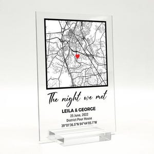Może przedstawiać: Przezroczysty nadruk na akrylu z czarno-białą mapą miasta, czerwonym sercem oznaczającym lokalizację i tekstem "The night we met". Poniżej napis "LEILA & GEORGE, 25 czerwca 2022, District Pour House, 39&deg;01'36.5"N 94&deg;44'05.1"W."