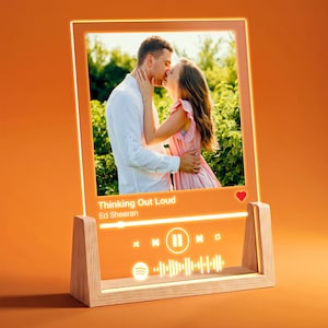 May include: A rectangular acrylic plaque with a light-up frame, featuring a photo of a couple kissing. The display shows the song title Thinking Out Loud by Ed Sheeran, a red heart icon, a progress bar, playback controls, and a Spotify code.