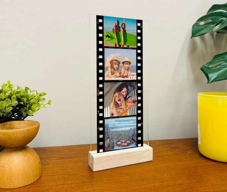 A black film reel frame with four photos inside on a table