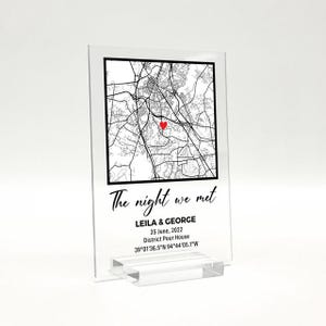 May include: A clear acrylic map print featuring a black and white city map, a red heart marking a location, and the text "The night we met." Below, it reads "LEILA & GEORGE, 25 June, 2022, District Pour House, 39&deg;01'36.5"N 94&deg;44'05.1"W."