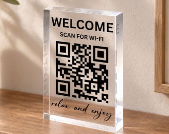 Może przedstawiać: Prostokątny blok z przezroczystego akrylu z czarnym nadrukiem tekstowym i kodem QR. Tekst brzmi WELCOME, SCAN FOR WI-FI oraz relax and enjoy. Tabliczka jest przezroczysta, ma gładkie, polerowane wykończenie i stoi pionowo na płaskiej powierzchni.