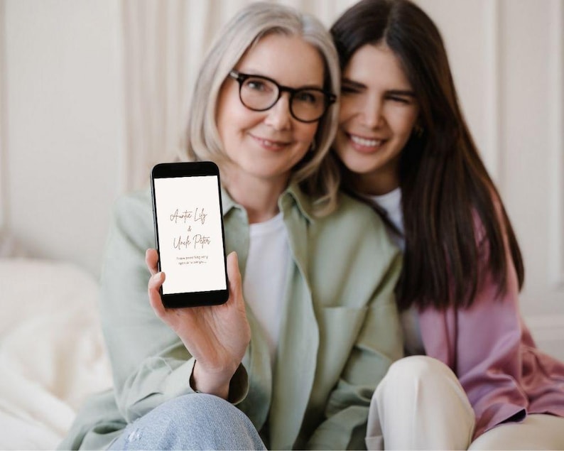 May include: A black smartphone showing the text "Auntie Lily & Uncle Peter" in a stylish script. The phone is held by a person wearing glasses and a light green shirt, with another person smiling beside them. The background is soft and blurred.