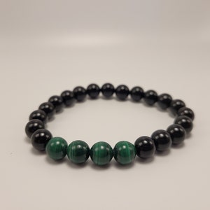 May include: A black and green beaded bracelet with alternating black and green beads. The bracelet is made of round beads.
