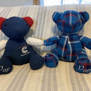 May include: Two handmade teddy bears. One is navy blue with red ears and white arms, the other is blue plaid. Both have the word "Pap" on their feet. The navy bear has text that reads "Cummins Industrial Center".