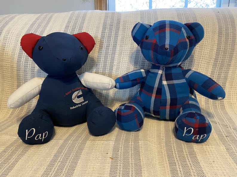 May include: Two handmade teddy bears. One is navy blue with red ears and white arms, the other is blue plaid. Both have the word "Pap" on their feet. The navy bear has text that reads "Cummins Industrial Center".