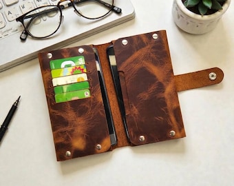 May include: A brown distressed leather wallet case with a snap closure, featuring multiple interior slots containing several colourful credit cards. The wallet is open, revealing a dark interior lining and silver-toned metal rivets at the corners.
