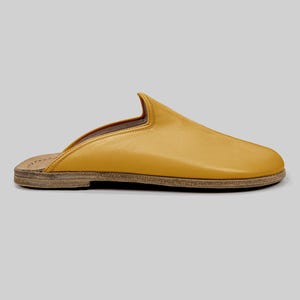 Flexible leather sole of handmade men's mustard mules, emphasizing zero-drop design for natural movement, alongside premium BespokyBarefoot packaging.