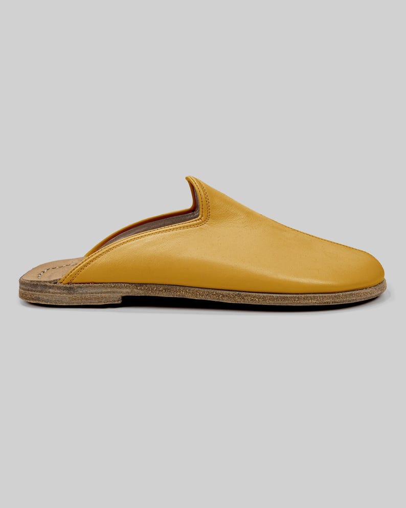 Flexible leather sole of handmade men's mustard mules, emphasizing zero-drop design for natural movement, alongside premium BespokyBarefoot packaging.