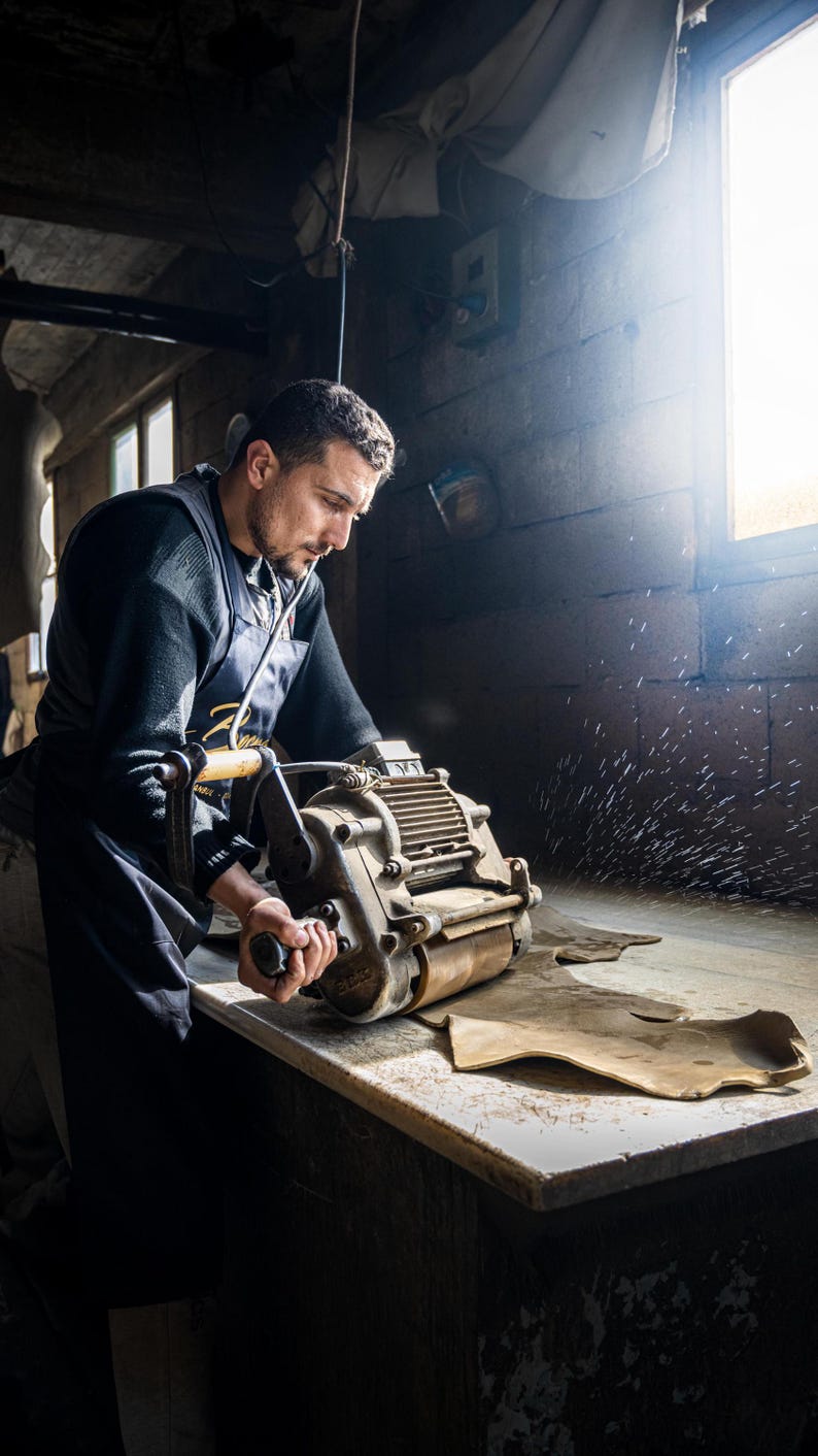 A man is working on a machine in a workshop, using a tool to operate the machine.