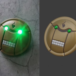 May include: A round, gold-colored robot face with green glowing eyes and a row of white teeth. The robot face has a black symbol on the top.