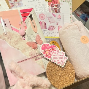 May include: A gift box containing a reading log, a pink butterfly-themed envelope with a pen and hair clip, a cork coaster, a wrapped item with a thank you sticker, and various stickers including one that reads Buy me books and call me a good girl.
