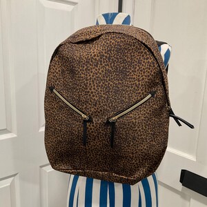 May include: A brown and black leopard print backpack with black zippers and gold zipper pulls.