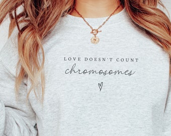 May include: A grey sweatshirt with the text "LOVE DOESN'T COUNT chromosomes" in black lettering. A small heart symbol is below the text.