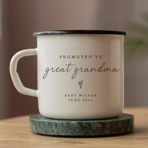 May include: White enamel mug with a black rim and handle. The mug has the text "Promoted to great grandma" with a heart symbol and the text "Baby Wilson June 2025".