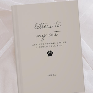 May include: A beige journal with the title "letters to my cat" in script. The cover includes a paw print graphic and the text "ALL THE THINGS I WISH I COULD TELL YOU." The name "SIMBA" is printed at the bottom.
