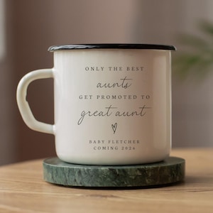 May include: White enamel mug with a black rim and handle. The mug features the text "ONLY THE BEST aunts GET PROMOTED TO great aunt" in black script, with a heart symbol and "BABY FLETCHER COMING 2026".