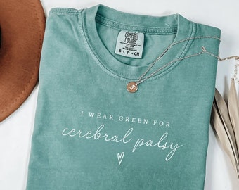 May include: A teal green t-shirt with the text "I wear green for cerebral palsy" in white lettering. A small heart is below the text.