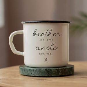 Puede incluir: Taza de esmalte blanco con borde y asa negros. La taza tiene el texto "brother est. 1995 uncle est. 2025" impreso en ella.