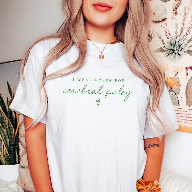 Peut inclure: T-shirt blanc avec le texte "Je porte du vert pour la paralysie c&eacute;r&eacute;brale" en lettres vertes avec un c&oelig;ur vert.
