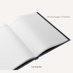 Może przedstawiać: Niebieski notes w linie z 150 stronami i 75 kartkami. Notes jest otwarty, a strony są puste. Na dole strony widnieje napis "Lune Design Shop".