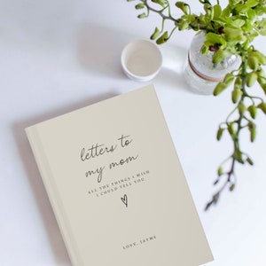 Peut inclure: Un journal beige avec le texte "letters to my mom" et "ALL THE THINGS I WISH I COULD TELL YOU" en &eacute;criture cursive noire. Un petit symbole de c&oelig;ur se trouve sous le texte. Le texte "LOVE, JAYME" est en bas du journal.