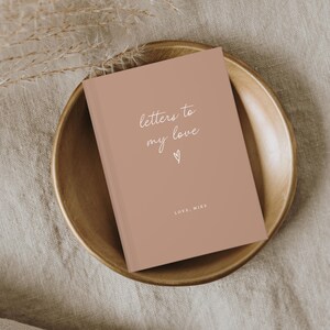 Może przedstawiać: Brązowy dziennik z tekstem "letters to my love" w białym piśmie. Dziennik ma małe serce narysowane pod tekstem i słowa "LOVE, MIKE" na dole.