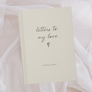 Może przedstawiać: Beżowy notes z tekstem "letters to my love" napisanym czarnym, ozdobnym pismem i małym symbolem serca. Nazwa autora, "KAYLA HALL", jest wydrukowana czarnym kolorem na dole okładki.