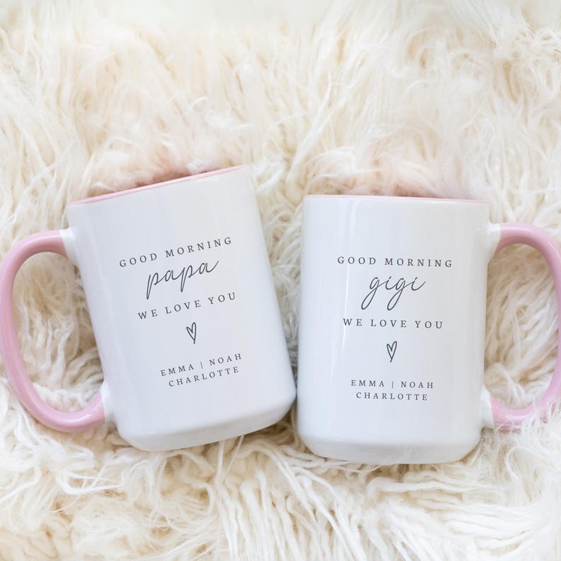 Puede incluir: Dos tazas de cer&aacute;mica blancas con asas e interiores rosas. Una taza dice "Good Morning Papa, We Love You" con nombres debajo. La otra dice "Good Morning Gigi, We Love You" con nombres debajo.