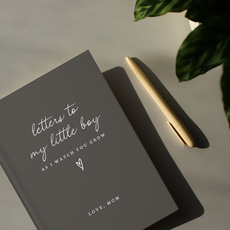 May include: A gray journal with the text "letters to my little boy as I watch you grow" and a heart symbol. The text "LOVE, MOM" is at the bottom of the journal.