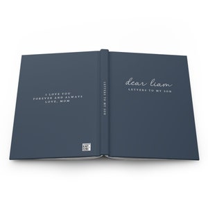 May include: Open journal with a dark blue cover. The left page reads "I LOVE YOU FOREVER AND ALWAYS LOVE, MOM" in white script. The right page says "dear liam LETTERS TO MY SON". The spine reads "LETTERS TO MY SON".