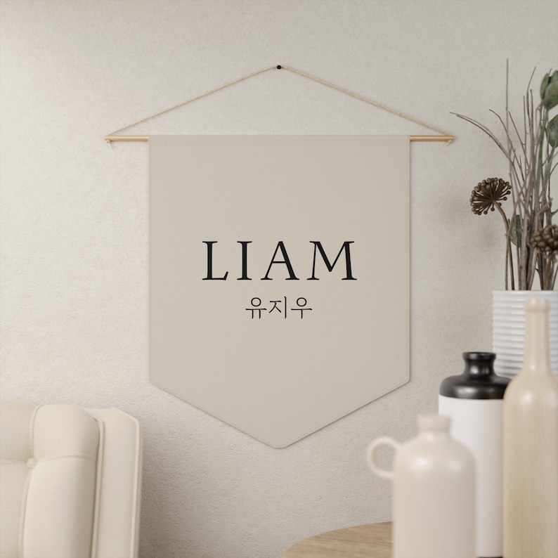 May include: A beige fabric banner with the name "LIAM" and the Korean text "유지우" in black lettering.
