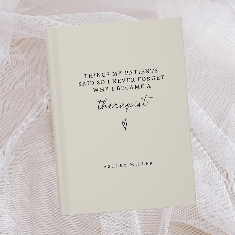 May include: A cream-colored journal with the text "THINGS MY PATIENTS SAID SO I NEVER FORGET WHY I BECAME A therapist" in black script. A small heart symbol is below the word "therapist". The author's name, Ashley Miller, is at the bottom.