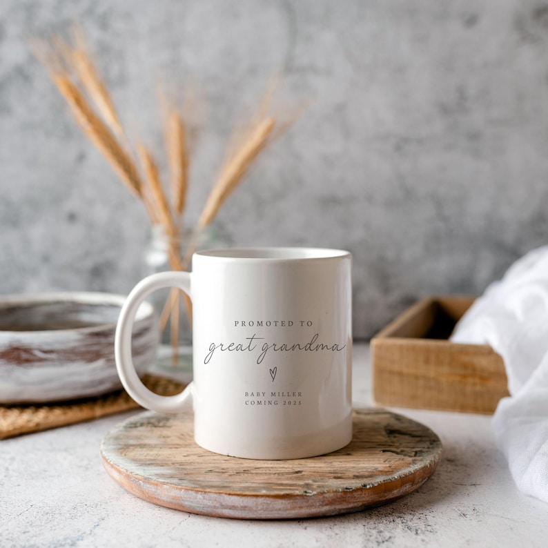May include: White ceramic mug with the text "Promoted to Great Grandma" and a small heart. Below the text is "Baby Miller Coming 2023".