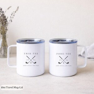 May include: Two white 10oz travel mugs with lids, each featuring a handle and a black graphic of crossed golf clubs and a golf ball. The left mug reads THIR-TEE 1996 AND STILL ON PAR, and the right mug reads FORE-TEE 1986 AND STILL ON PAR.
