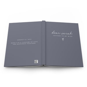 May include: Open journal with a gray cover. The left page has the date "August 27, 2022" and the text "Here's to a lifetime of love and happiness together." The right page reads "dear sarah LETTERS TO MY WIFE" with a heart symbol.