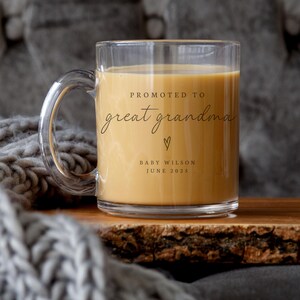 May include: A clear glass mug with a handle, filled with coffee. The mug has the text "Promoted to great grandma" with a heart symbol and the text "Baby Wilson June 2023".