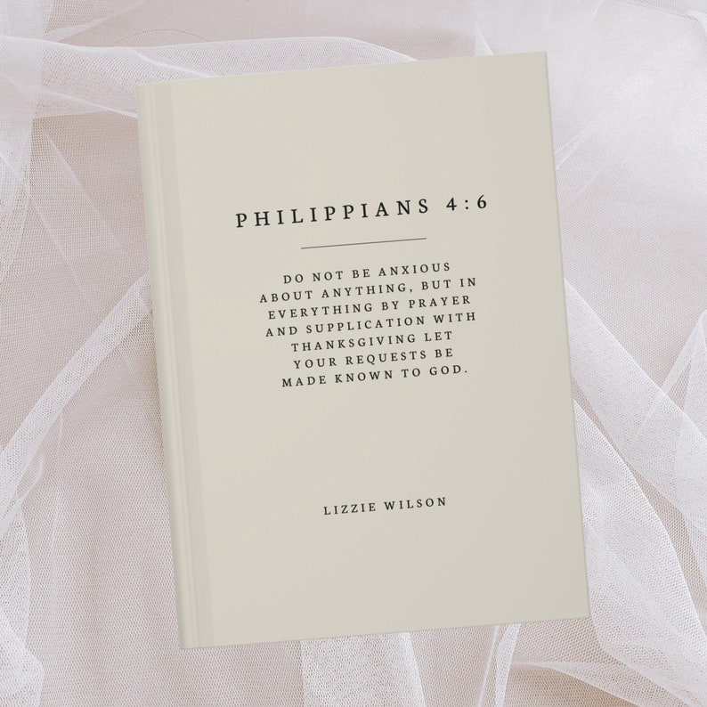May include: A beige book with the text "Philippians 4:6" and a quote from the Bible verse. The quote reads "Do not be anxious about anything, but in everything by prayer and supplication with thanksgiving let your requests be made known to God." The book is signed "Lizzie Wilson".