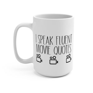May include: White ceramic coffee mug with a black design that says "I speak fluent movie quotes" with three black film camera icons.