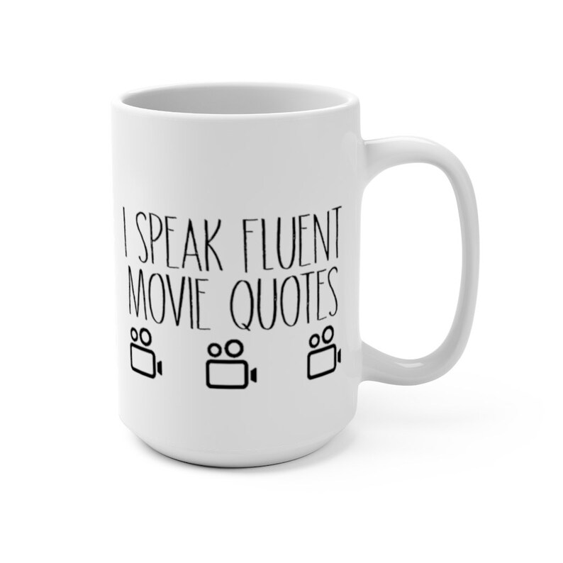 May include: White ceramic coffee mug with black text that reads "I speak fluent movie quotes" and three black film camera icons.